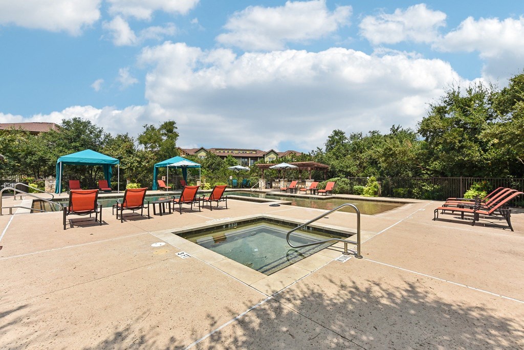 the reserve at the falls pool and hot tub with chairs and umbrellas at Lakeline East Apartments, Cedar Park