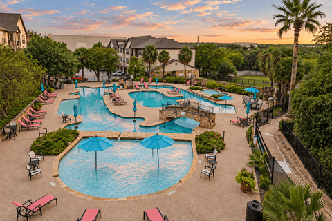 A large outdoor swimming pool surrounded by lounge chairs and umbrellas.
