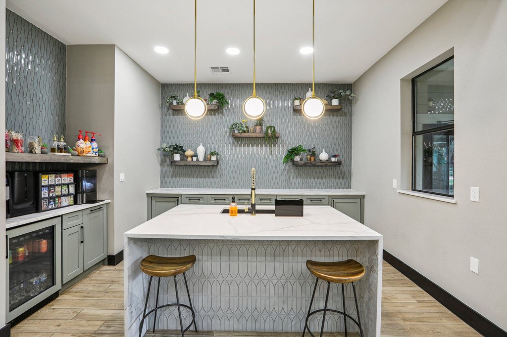 a kitchen with a large island and three stools at Ventana Oaks Apartments, Texas