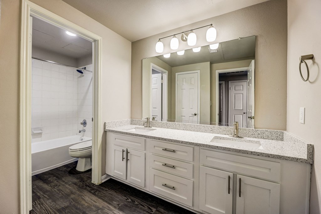 a bathroom with white cabinets and a mirror and a toilet at Ventana Oaks Apartments, Austin