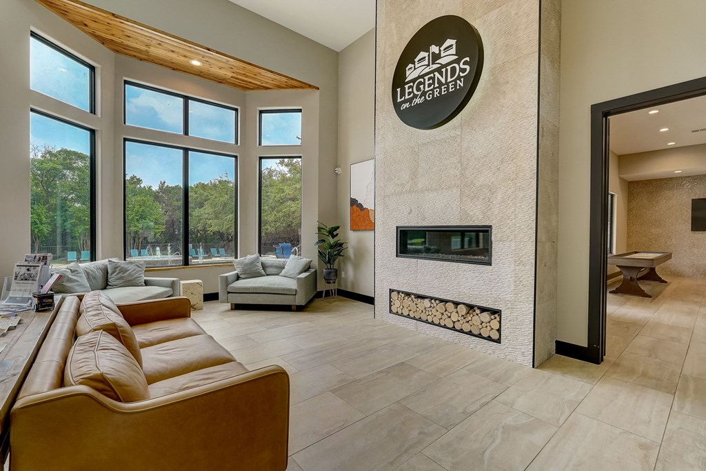 the living room has a fireplace and a large window at Legends on the Green Apartments, Texas, 78232