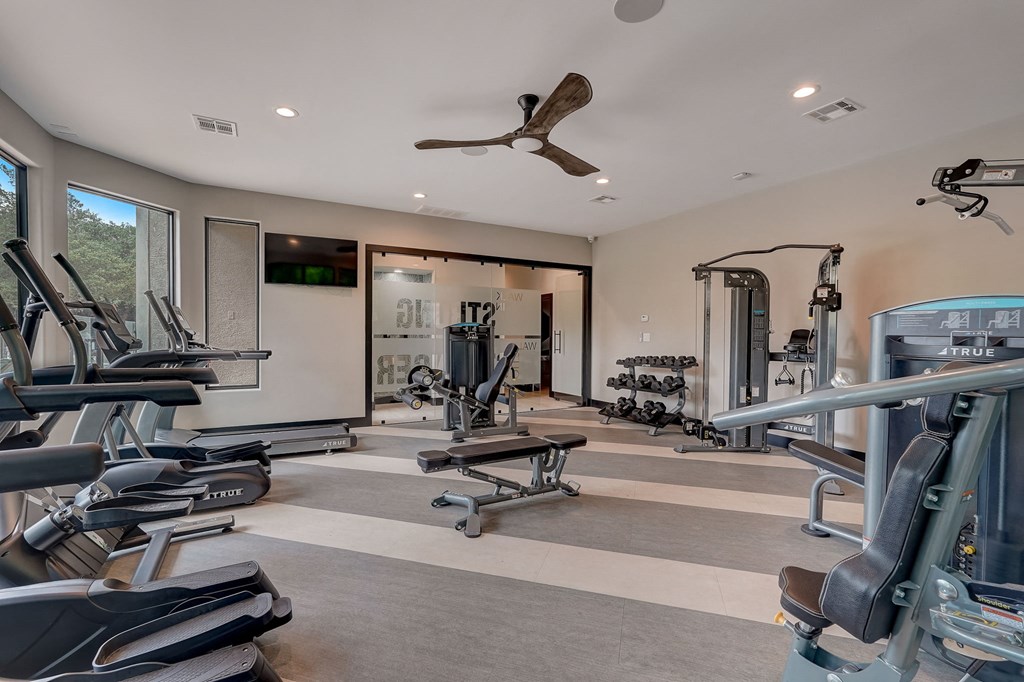 a gym with weights and cardio equipment in a home for sale at Legends on the Green Apartments, San Antonio