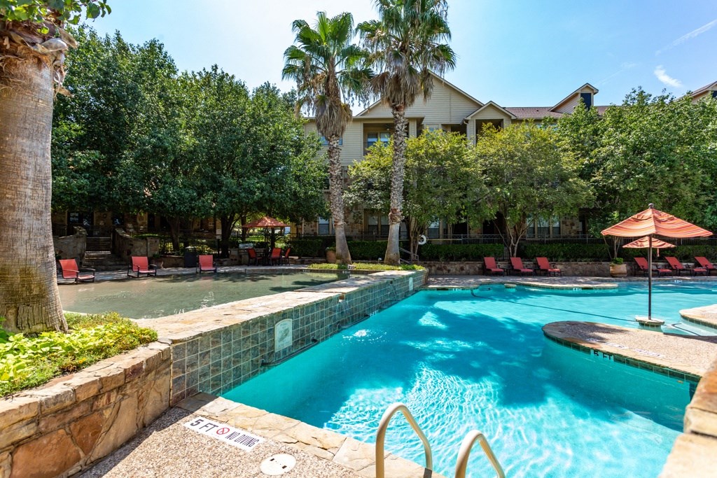 a resort style swimming pool with lounge chairs and trees in the background at The Verandah, Austin, TX, 78726