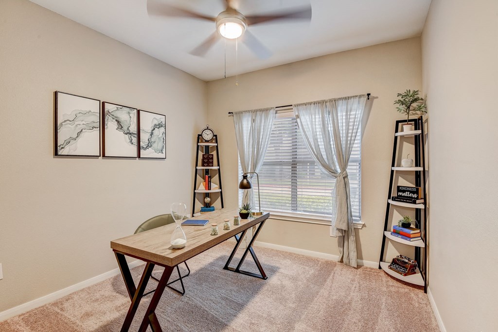 an office with a large window and a desk with a ceiling fan at Artisan Apartments & Shops, Austin, TX, 78729
