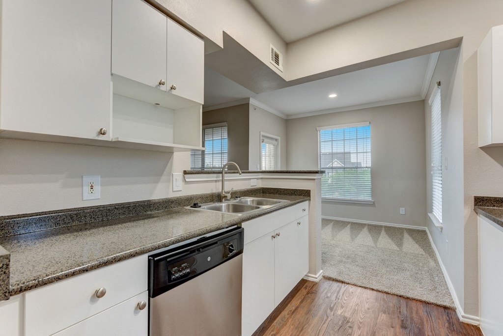 an empty kitchen with white cabinets and granite counter tops