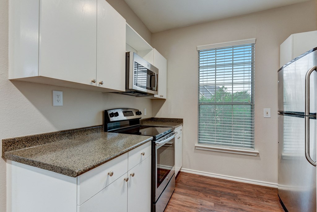 a kitchen with white cabinets and granite counter tops and a stainless steel refrigerator