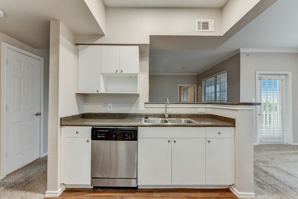 an empty kitchen with white cabinets and a stainless steel dishwasher