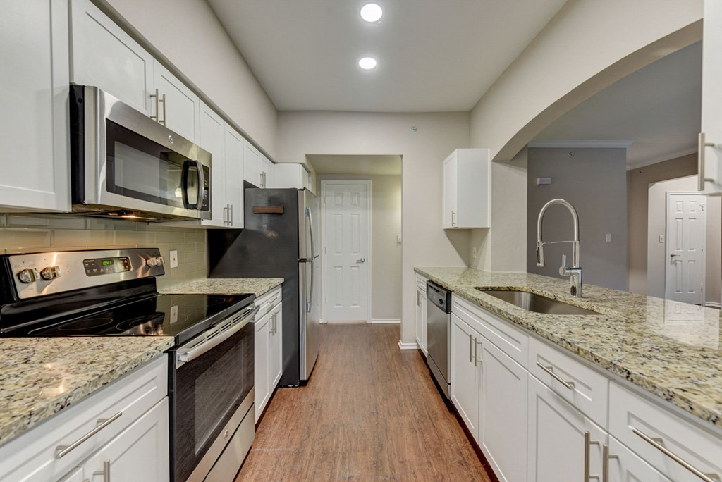 a kitchen with granite counter tops and white cabinets at Stone Oak @ Parmer, Austin, TX