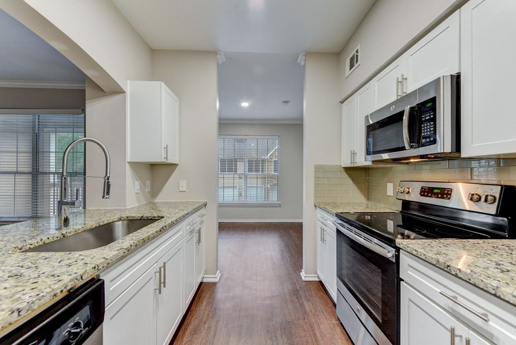 an empty kitchen with white cabinets and granite counter tops at Stone Oak @ Parmer, Austin, Texas
