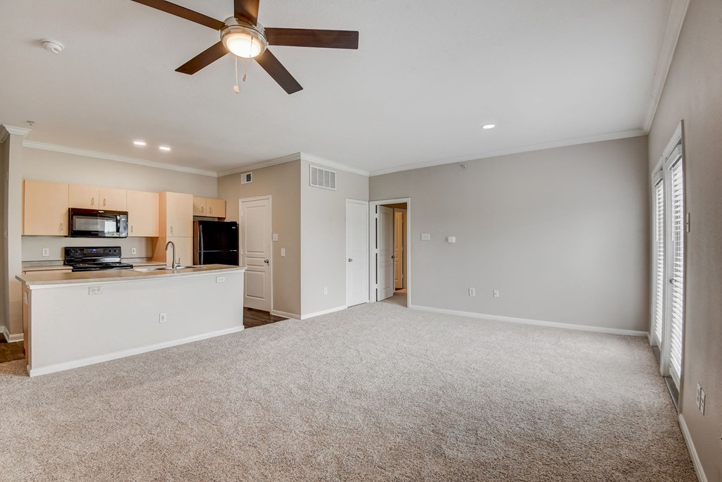 an empty living room with a ceiling fan and a kitchen at Artisan Apartments & Shops, Austin, Texas