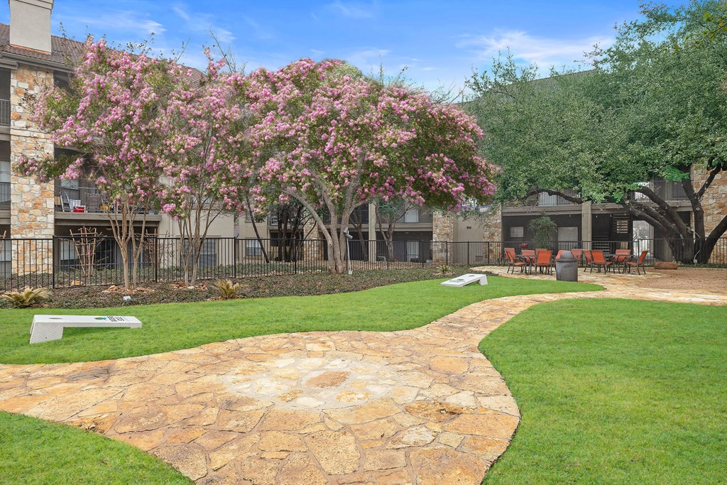 a courtyard with a stone path and a pink flowering tree at Waters Edge Apartment Homes, Georgetown