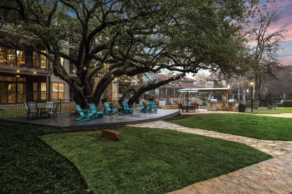 a patio with blue chairs and a tree at Waters Edge Apartment Homes, Texas, 78626