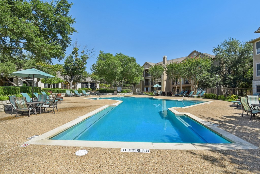 pool and patio with tables and chairs and buildings at Sonterra Apartment Homes, Austin, TX
