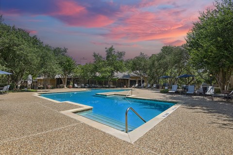 a swimming pool at a resort with trees and a pink sky