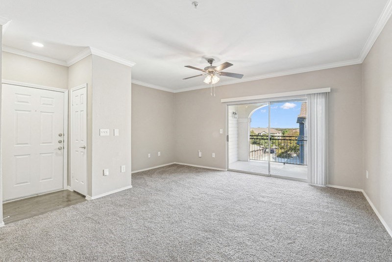 an empty living room with a ceiling fan and a window at TalaVera Apartments, Texas