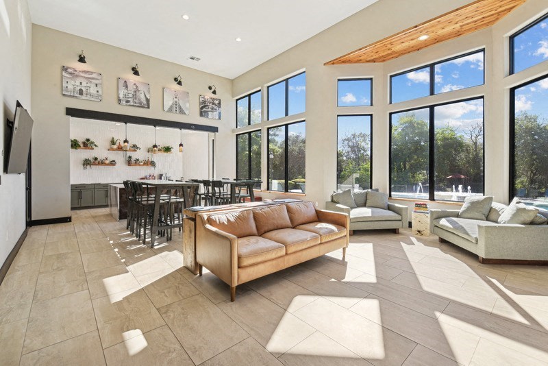 a living room with a couch and a table in front of a large window at Legends on the Green Apartments, Texas