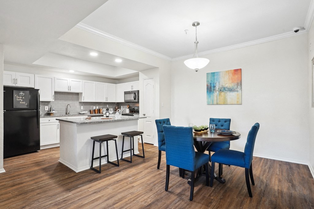 a living room with a table and chairs and a kitchen with a sink at La Ventura Apartments, Texas, 75093