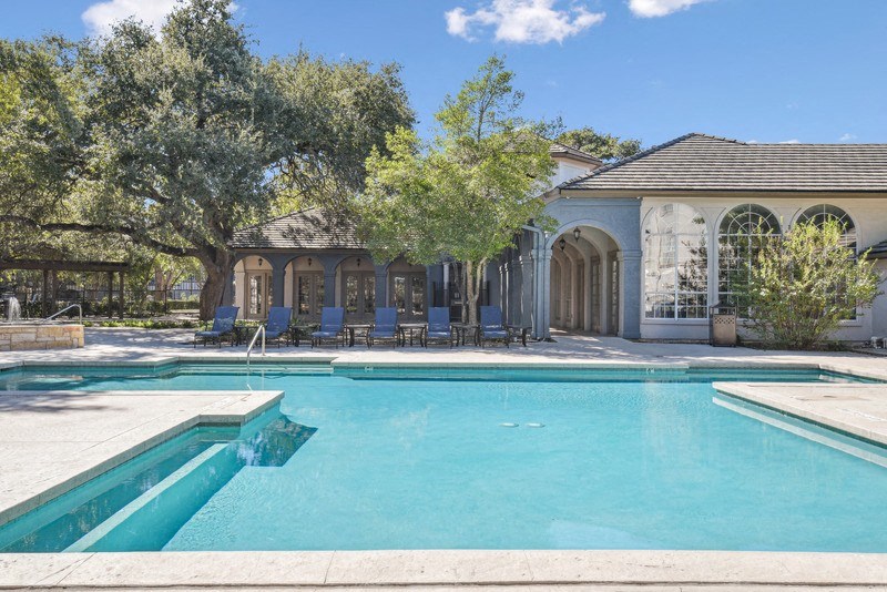 a swimming pool with a house in the background at TalaVera Apartments, San Antonio, TX