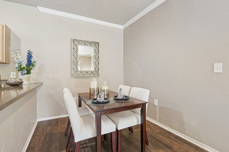 a dining room with a table and chairs and a mirror at Legends on the Green Apartments, San Antonio, Texas