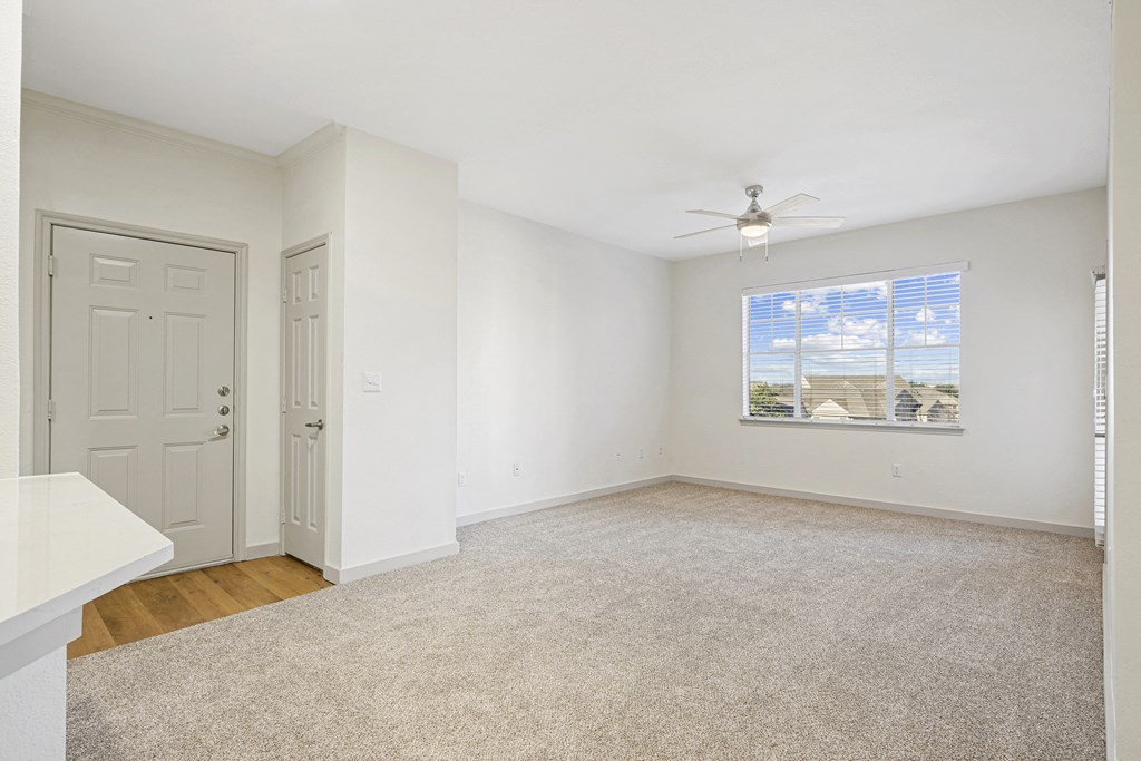an empty living room with white walls and a ceiling fan at The Legends at Eagle Mountain Lake, Fort Worth
