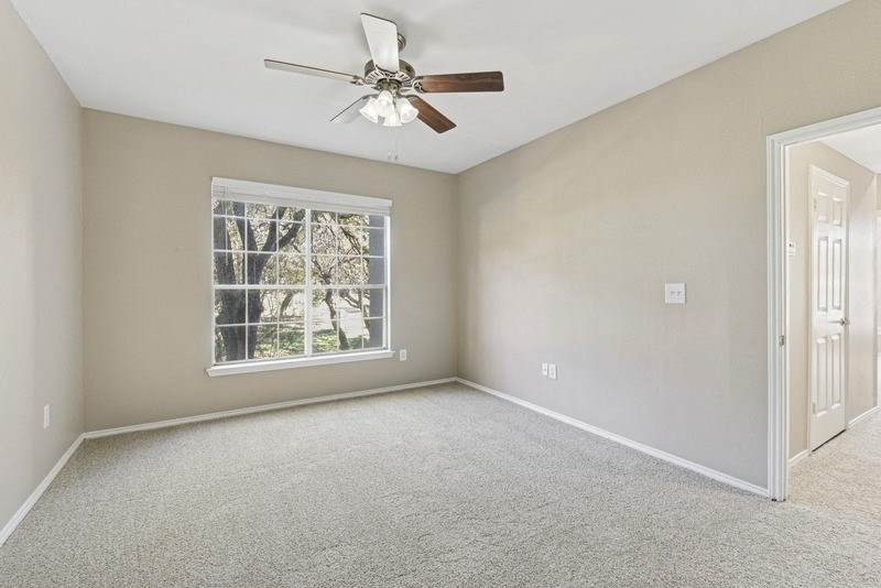 an empty bedroom with a ceiling fan and a window at Legends on the Green Apartments, San Antonio 78232