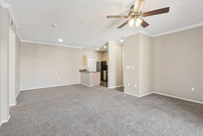 the living room and kitchen of a new home with a ceiling fan at TalaVera Apartments, San Antonio