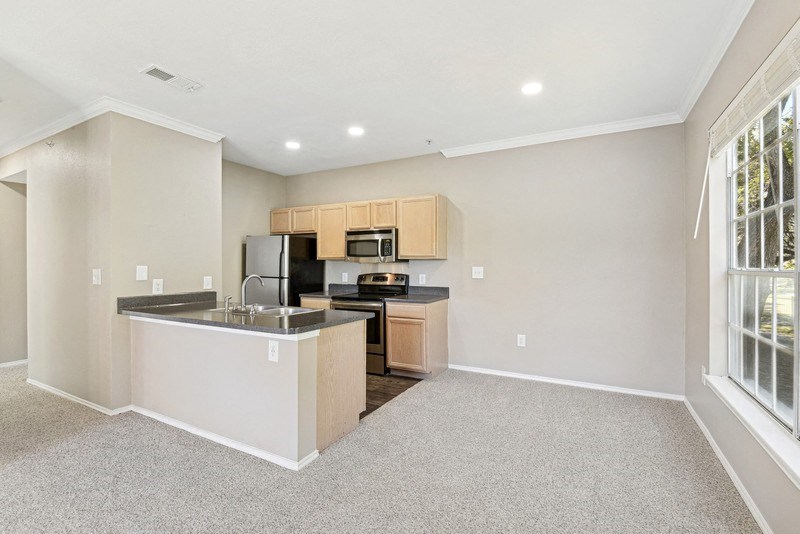 the living room and kitchen of a home with a large window at Legends on the Green Apartments, San Antonio, TX, 78232