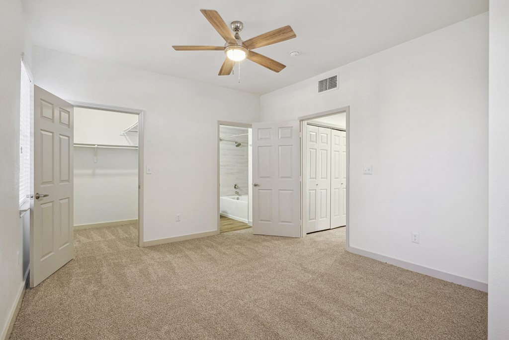 the living room of an empty apartment with white walls and a ceiling fan at The Legends at Eagle Mountain Lake, Fort Worth