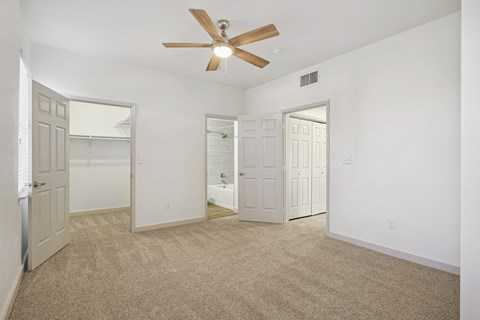 the living room of an empty apartment with white walls and a ceiling fan at The Legends at Eagle Mountain Lake, Fort Worth