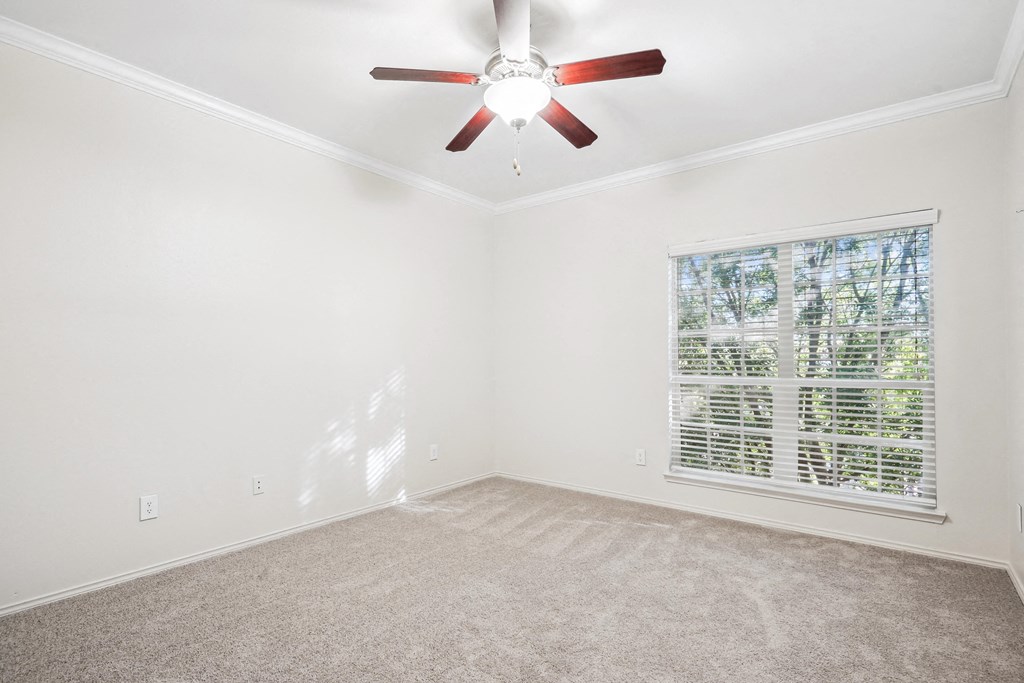 an empty living room with a ceiling fan and a window at La Ventura Apartments, Plano, 75093