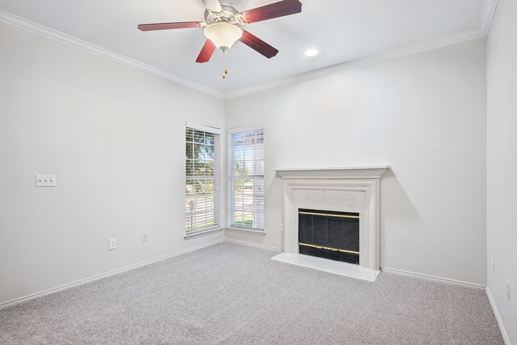an empty living room with a fireplace and a ceiling fan at La Ventura Apartments, Plano, TX, 75093