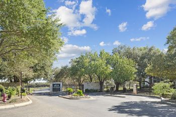 the entrance to a park with trees and a road