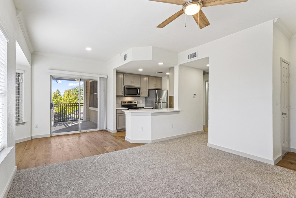 an empty living room with a kitchen and a ceiling fan at The Legends at Eagle Mountain Lake, Fort Worth