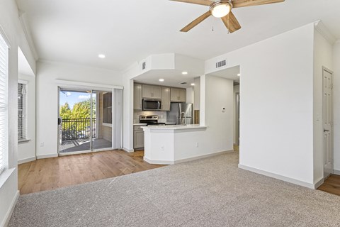 an empty living room with a kitchen and a ceiling fan at The Legends at Eagle Mountain Lake, Fort Worth