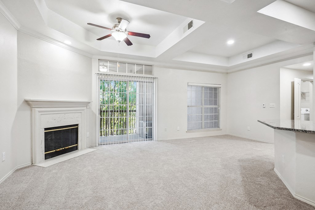 an empty living room with a fireplace and a ceiling fan at La Ventura Apartments, Plano, 75093