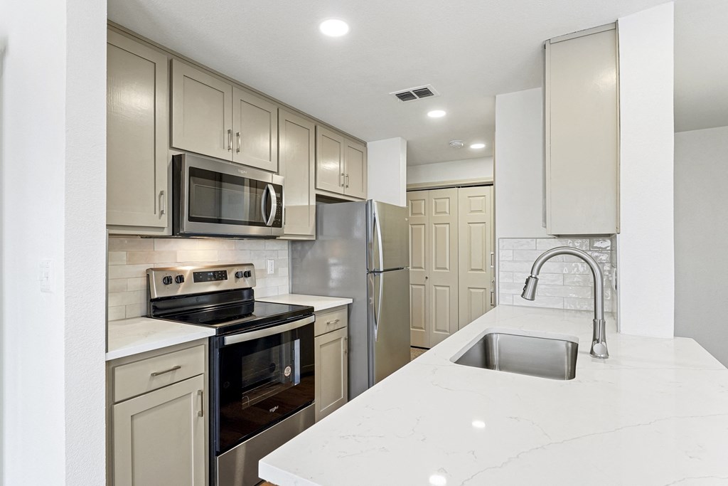 a white kitchen with stainless steel appliances and white counter tops at The Legends at Eagle Mountain Lake, Fort Worth, Texas