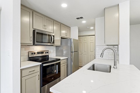 a white kitchen with stainless steel appliances and white counter tops at The Legends at Eagle Mountain Lake, Fort Worth, Texas