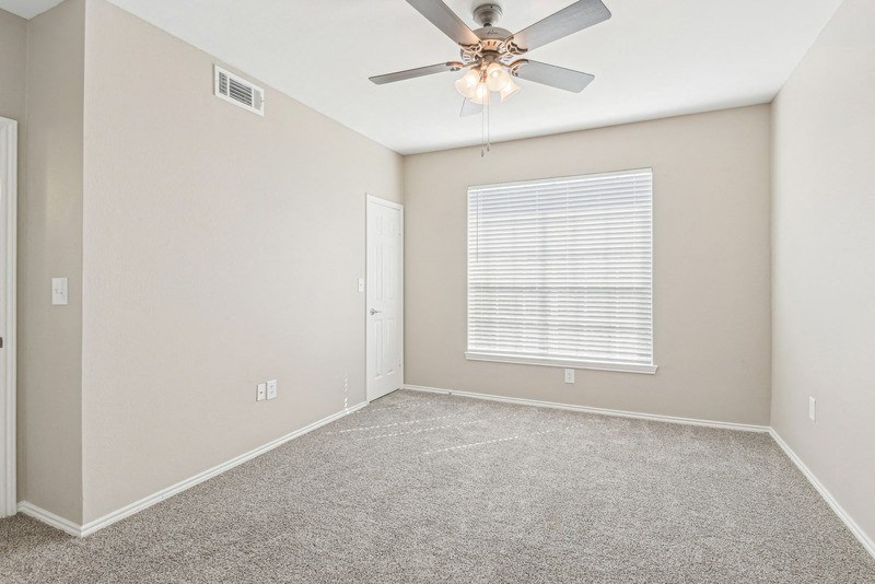 an empty room with a ceiling fan and a window at TalaVera Apartments, San Antonio, Texas