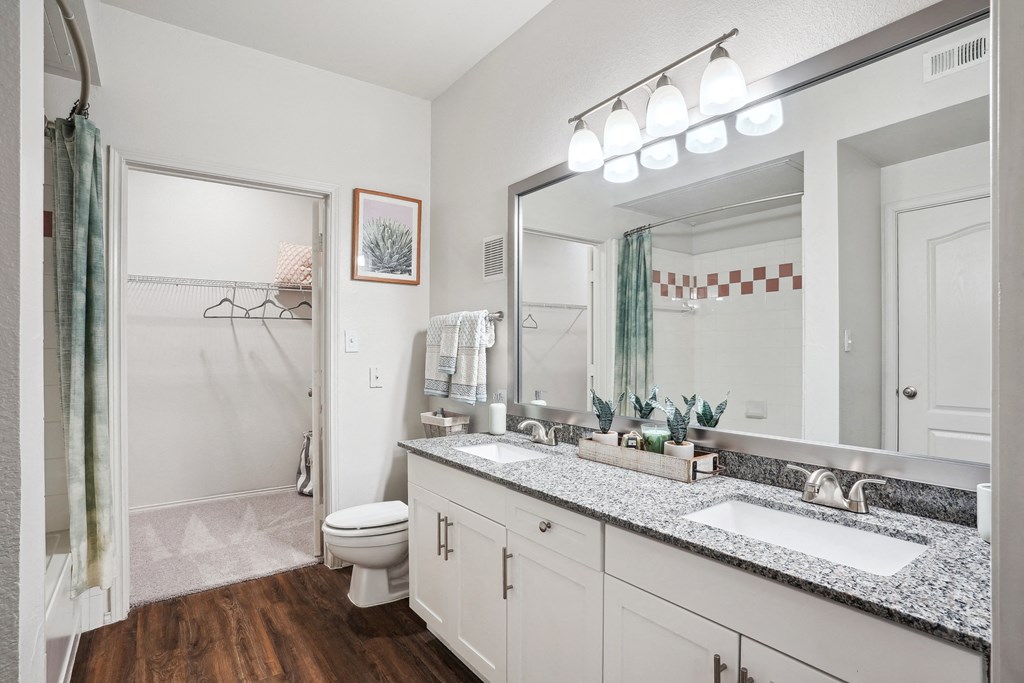 a bathroom with a large mirror and a sink and a toilet at La Ventura Apartments, Plano, Texas
