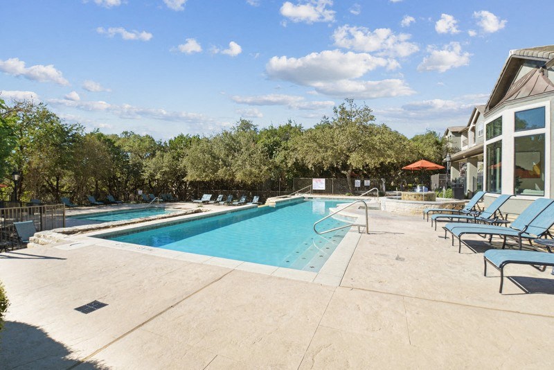 a swimming pool in a resort with chairs and a blue sky stock images at Legends on the Green Apartments, Texas