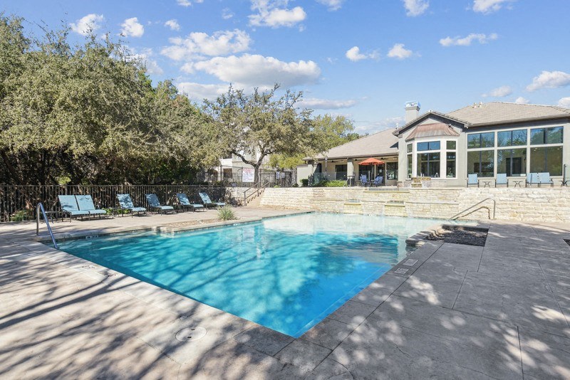 a swimming pool with a house in the background at Legends on the Green Apartments, San Antonio