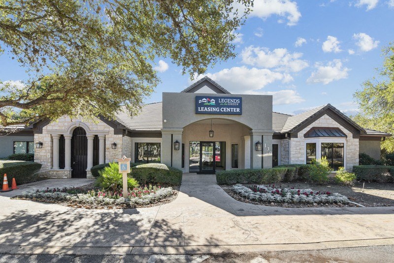 the leasing office at the leasing center atrium in front of a building with trees at Legends on the Green Apartments, San Antonio 78232