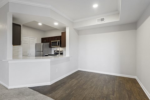 an empty living room with a kitchen and a hard wood floor at The Legends at Eagle Mountain Lake, Fort Worth, TX