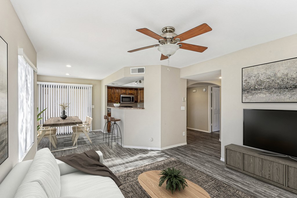 A living room with a white couch and a ceiling fan. at San Montego Apartments, Mesa