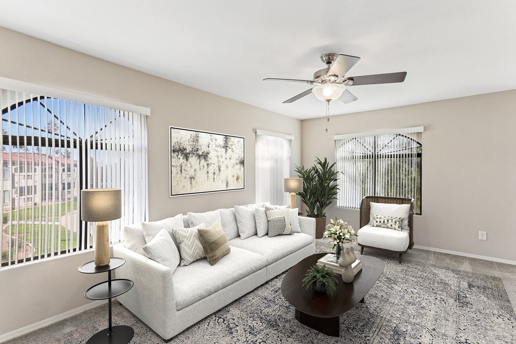 A living room with a white couch, a coffee table, and a ceiling fan. at San Montego Apartments, Arizona