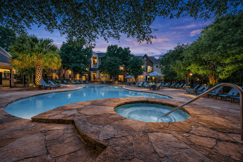 Pool and spa area at twilight with seating at Stone Oak @ Parmer Apartments, Texas