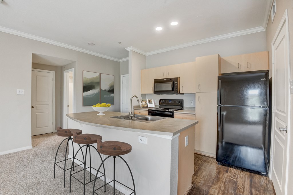 a kitchen with a large island with three stools at Artisan Apartments & Shops, Austin, TX