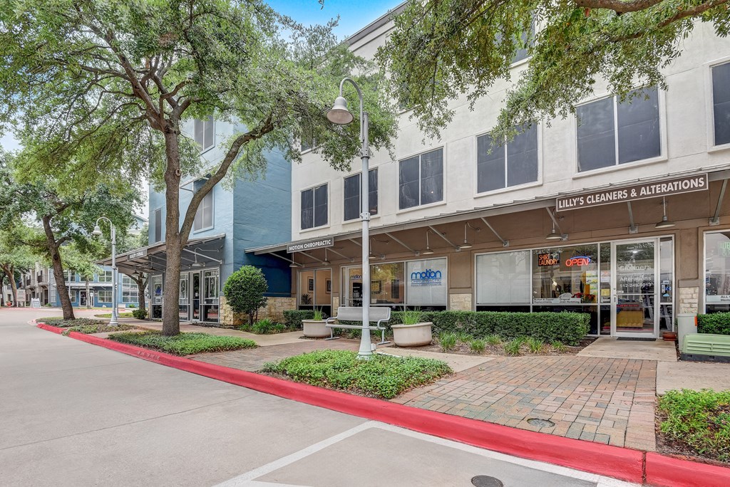 a building with a sidewalk and trees in front of it at Artisan Apartments & Shops, Austin, TX