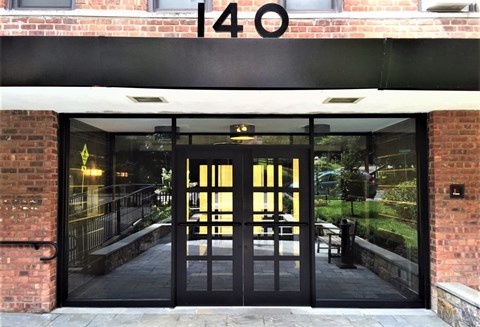 The entrance to a building with a glass door and a brick wall.