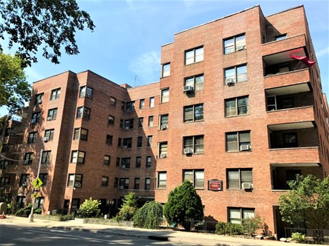 A red brick building with a flag on the top floor.